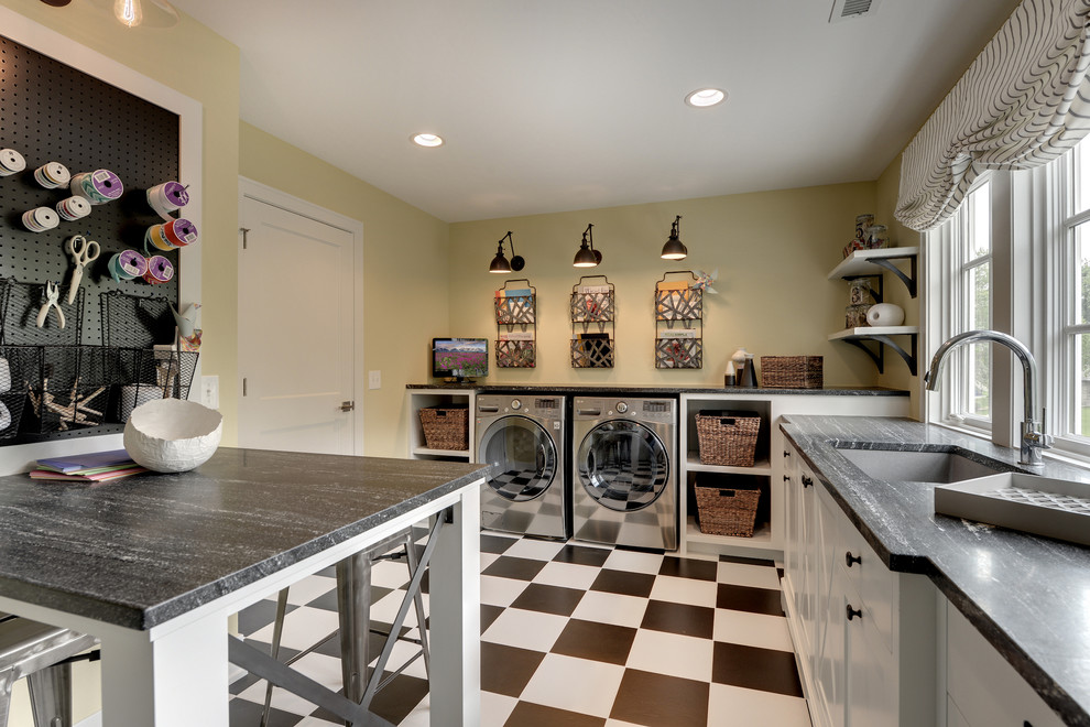 Imagen de lavadero tradicional con puertas de armario blancas, lavadora y secadora juntas, suelo multicolor y encimeras grises