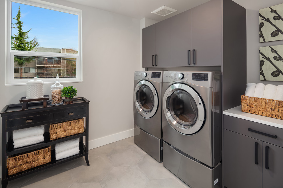 Medium sized contemporary single-wall separated utility room in Seattle with porcelain flooring, a side by side washer and dryer, flat-panel cabinets, grey cabinets, grey walls, grey floors and white worktops.