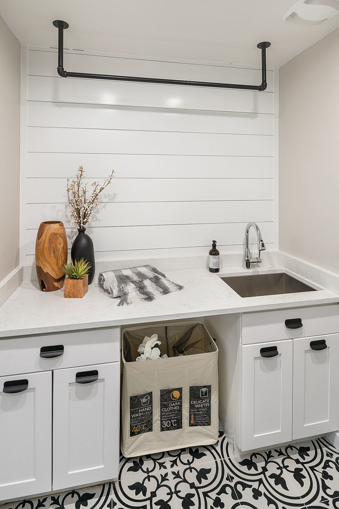Inspiration for a small farmhouse galley separated utility room in Seattle with a submerged sink, shaker cabinets, white cabinets, engineered stone countertops, grey walls, ceramic flooring, a side by side washer and dryer, black floors and white worktops.