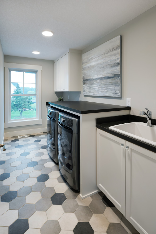 This is an example of a medium sized traditional galley separated utility room in Minneapolis with a built-in sink, shaker cabinets, white cabinets, laminate countertops, white walls, porcelain flooring, a side by side washer and dryer, multi-coloured floors and black worktops.