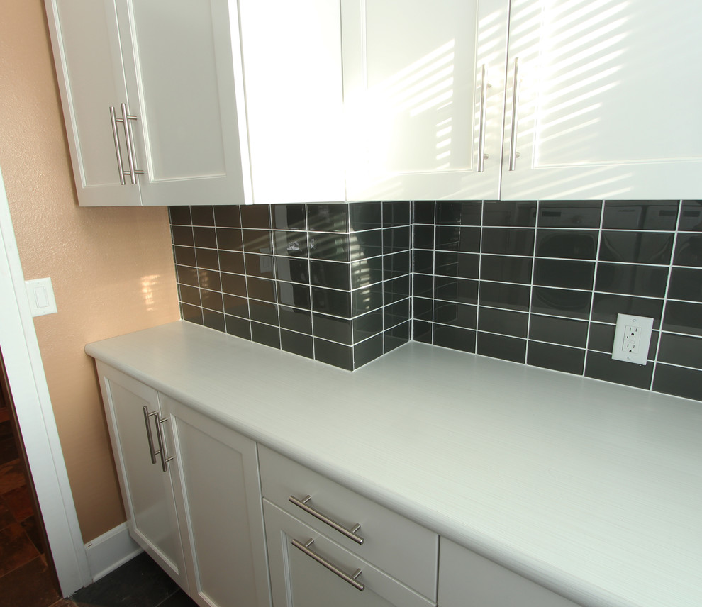 Klassisk inredning av en liten parallell tvättstuga enbart för tvätt, med luckor med infälld panel, vita skåp, laminatbänkskiva, beige väggar, skiffergolv, en tvättmaskin och torktumlare bredvid varandra och flerfärgat golv