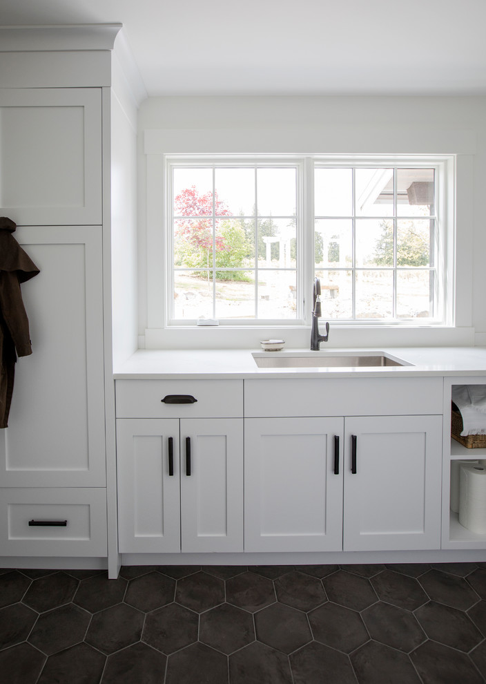 Inredning av en lantlig parallell tvättstuga enbart för tvätt, med skåp i shakerstil, vita skåp, marmorbänkskiva, vita väggar, klinkergolv i terrakotta, en tvättpelare, svart golv och en undermonterad diskho