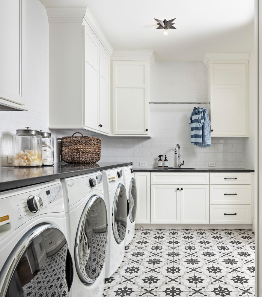 This is an example of a large rural l-shaped utility room in Detroit with a submerged sink, shaker cabinets, black cabinets, grey walls, a side by side washer and dryer, multi-coloured floors and black worktops.