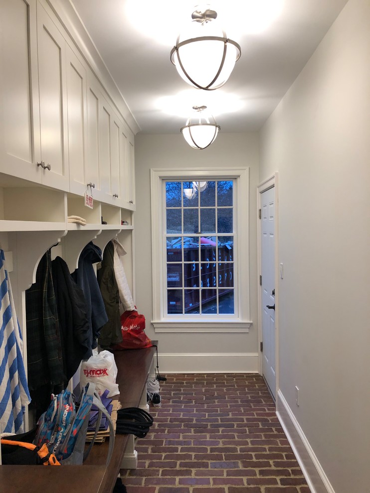 Immagine di una piccola lavanderia multiuso minimal con ante lisce, ante bianche, pareti bianche, pavimento in mattoni, lavatrice e asciugatrice affiancate e pavimento multicolore