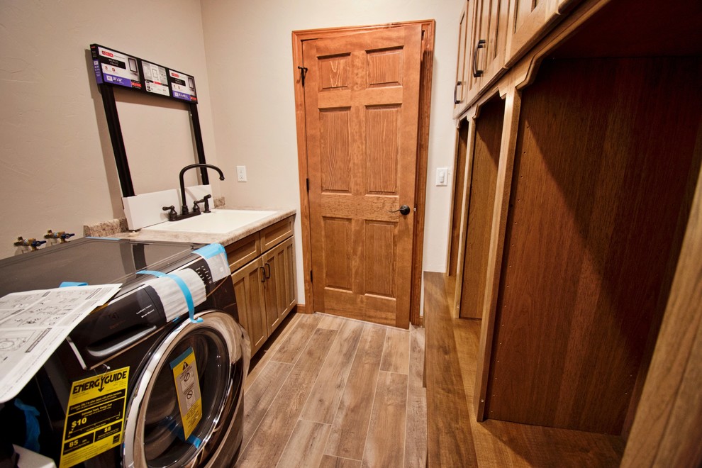 This is an example of a large country u-shaped utility room in Other with an utility sink, recessed-panel cabinets, medium wood cabinets, laminate countertops, white walls, medium hardwood flooring, a side by side washer and dryer, brown floors and brown worktops.