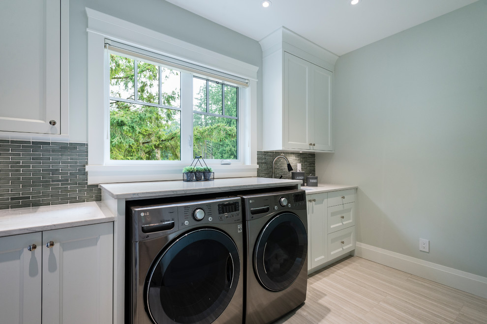 Design ideas for a large traditional single-wall utility room in Vancouver with a submerged sink, recessed-panel cabinets, white cabinets, engineered stone countertops, white walls, porcelain flooring, a side by side washer and dryer and grey floors.