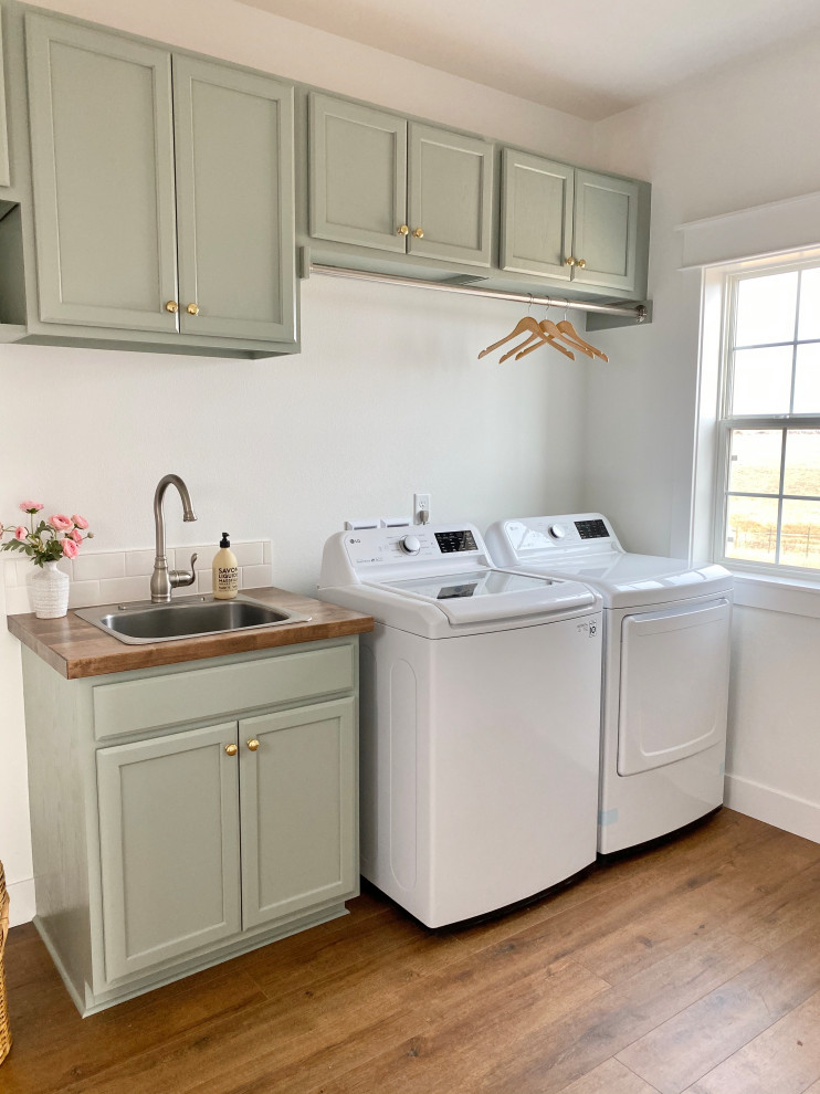Inspiration for a country laminate floor and brown floor utility room remodel in Denver with a drop-in sink, shaker cabinets, green cabinets, wood countertops, white walls, a side-by-side washer/dryer and brown countertops
