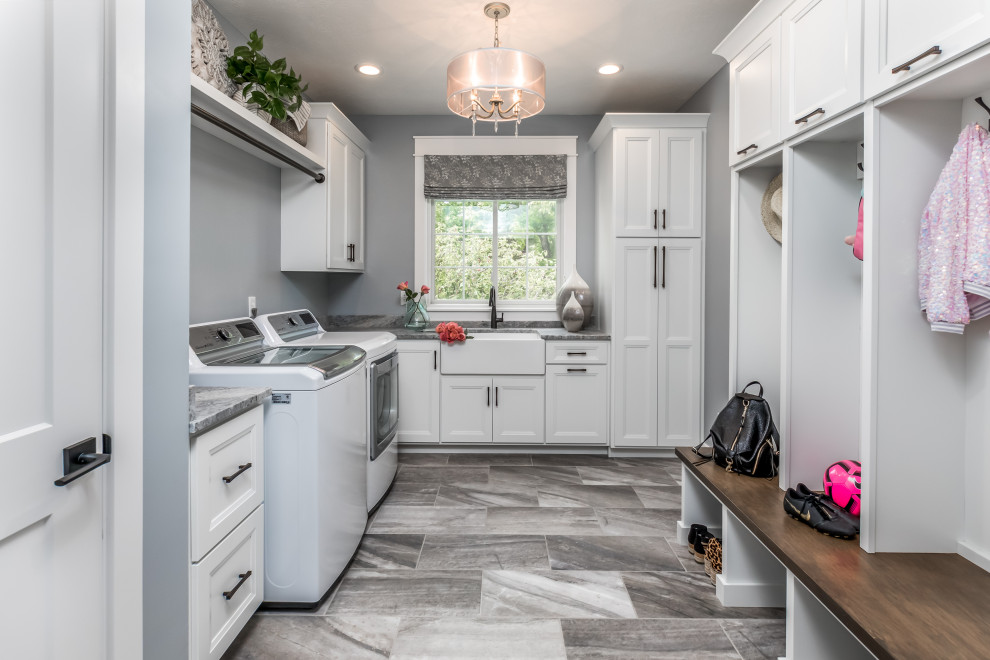 Example of a transitional l-shaped gray floor utility room design in Indianapolis with a farmhouse sink, recessed-panel cabinets, white cabinets, gray walls and gray countertops