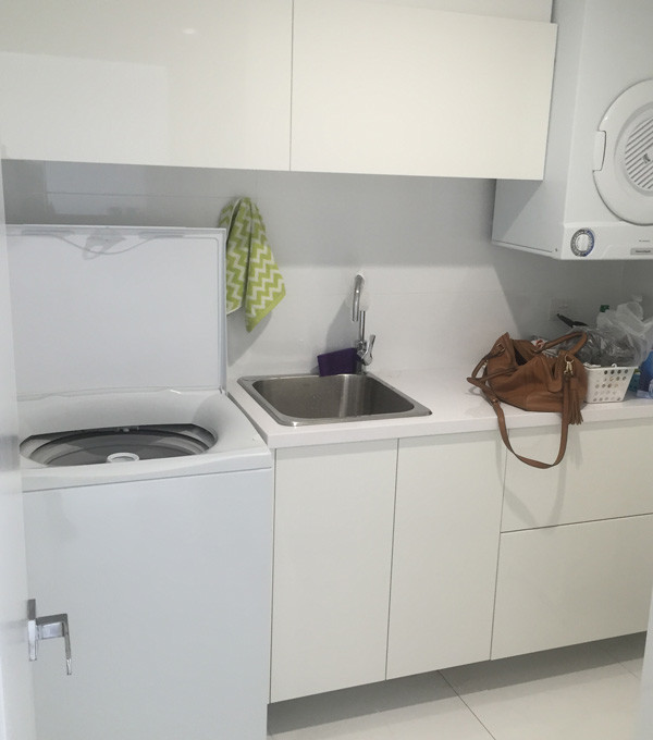 Idee per una sala lavanderia minimalista di medie dimensioni con lavatoio, top in laminato e lavatrice e asciugatrice a colonna