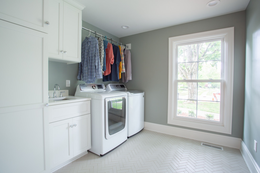 コロンバスにあるお手頃価格の中くらいなトラディショナルスタイルのおしゃれな洗濯室 (I型、アンダーカウンターシンク、シェーカースタイル扉のキャビネット、白いキャビネット、クオーツストーンカウンター、白いキッチンパネル、クオーツストーンのキッチンパネル、緑の壁、セラミックタイルの床、左右配置の洗濯機・乾燥機、ベージュの床、白いキッチンカウンター) の写真