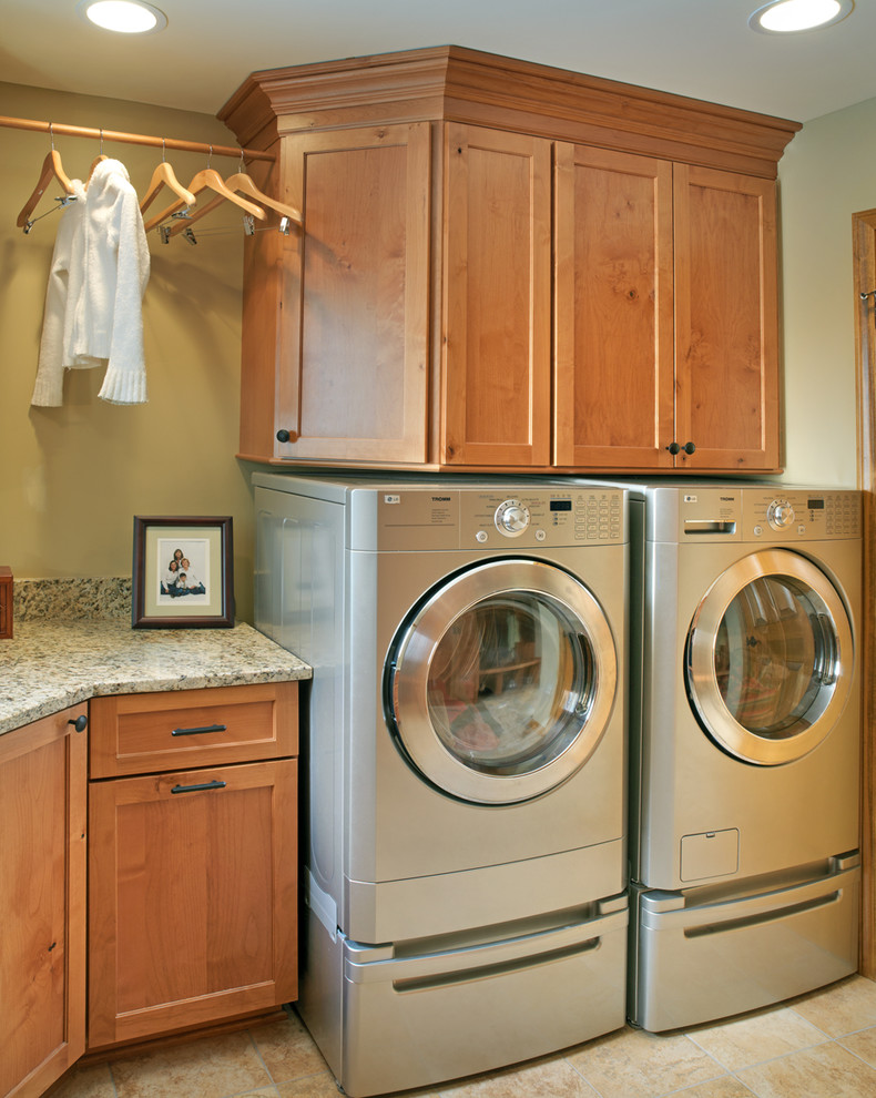 Idéer för en klassisk tvättstuga, med en tvättmaskin och torktumlare bredvid varandra, luckor med infälld panel, skåp i mellenmörkt trä, granitbänkskiva, klinkergolv i keramik och beige väggar