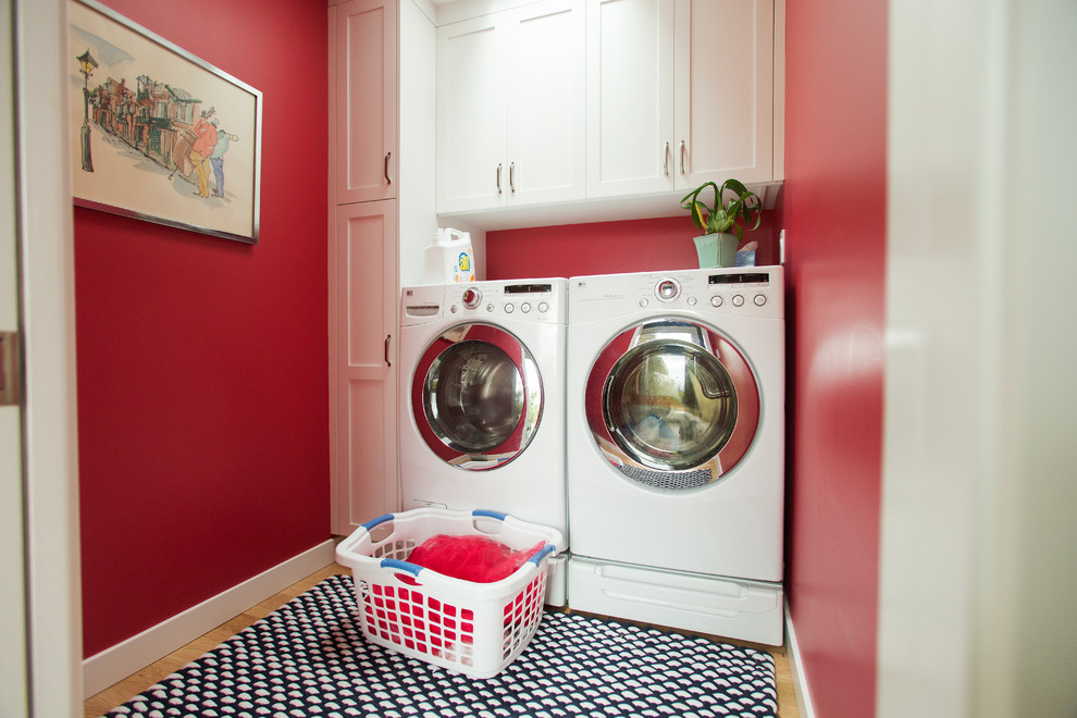 サンフランシスコにある高級な中くらいなコンテンポラリースタイルのおしゃれな洗濯室 (I型、シェーカースタイル扉のキャビネット、白いキャビネット、赤い壁、淡色無垢フローリング、左右配置の洗濯機・乾燥機) の写真