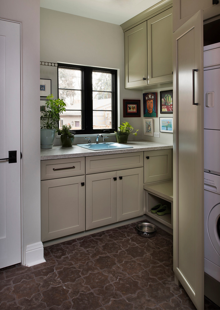 Tuscan utility room photo in Denver with a drop-in sink, a stacked washer/dryer and beige cabinets