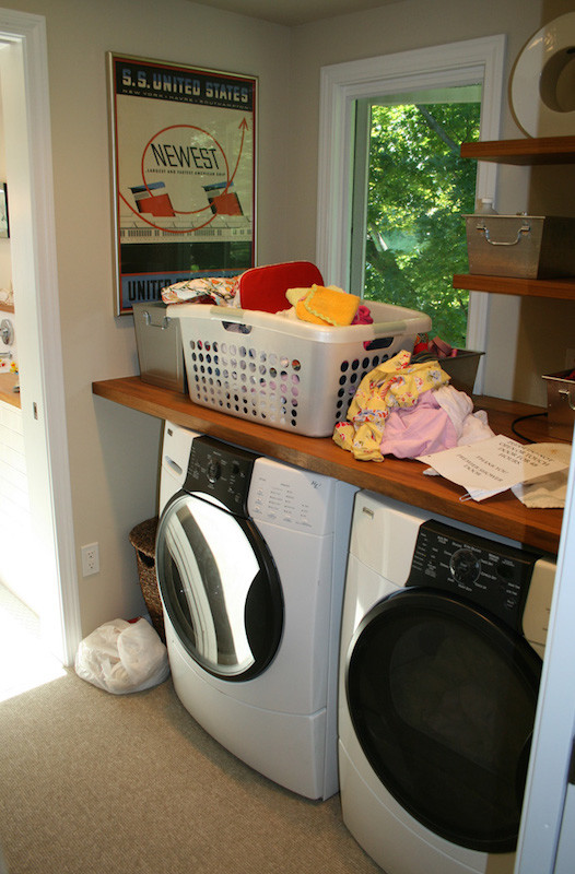 Example of a mid-sized classic single-wall carpeted dedicated laundry room design in New York with wood countertops, beige walls and a side-by-side washer/dryer