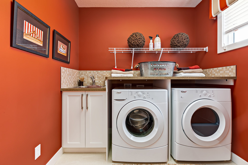 Ejemplo de cuarto de lavado lineal clásico renovado de tamaño medio con fregadero encastrado, armarios estilo shaker, puertas de armario blancas, paredes rojas y lavadora y secadora juntas