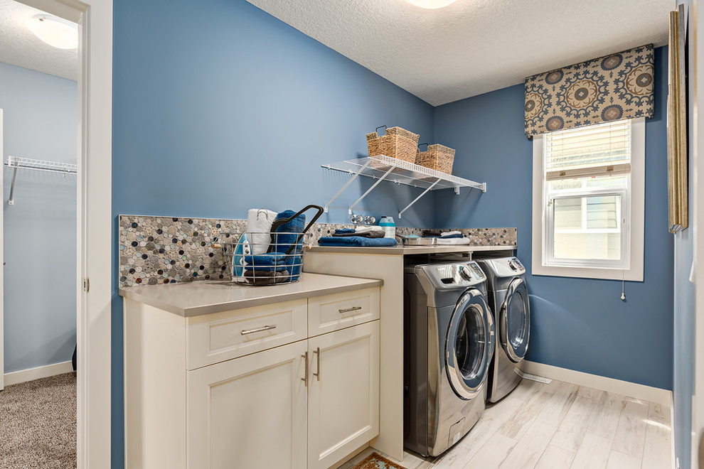 Inspiration för en liten vintage linjär tvättstuga enbart för tvätt, med luckor med infälld panel, beige skåp, blå väggar och en tvättmaskin och torktumlare bredvid varandra
