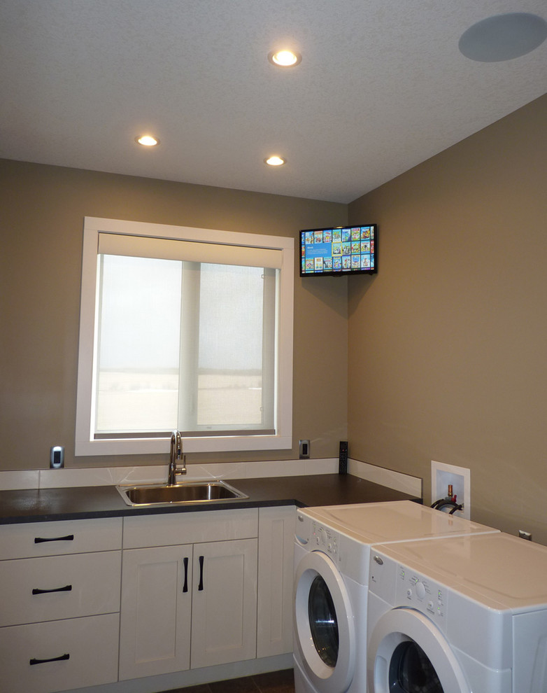 Small modern l-shaped separated utility room in Calgary with a single-bowl sink, shaker cabinets, white cabinets, laminate countertops, brown walls, lino flooring, a side by side washer and dryer, brown floors and brown worktops.