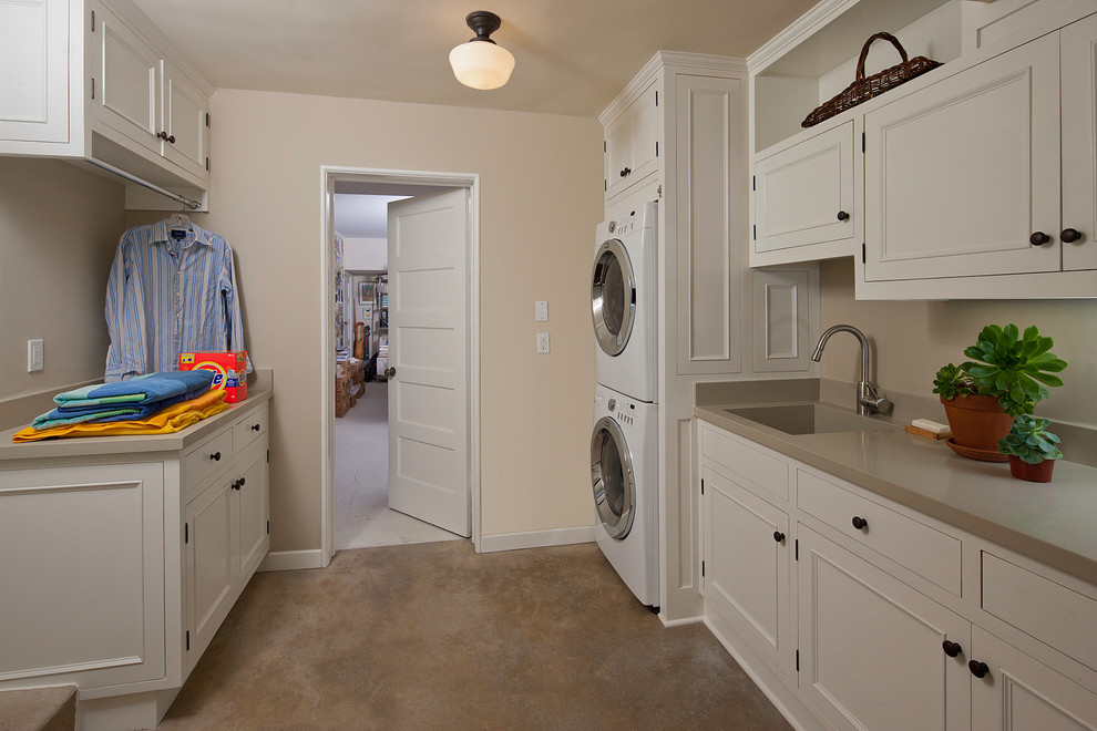 Elegant laundry room photo in Los Angeles with a stacked washer/dryer and white cabinets