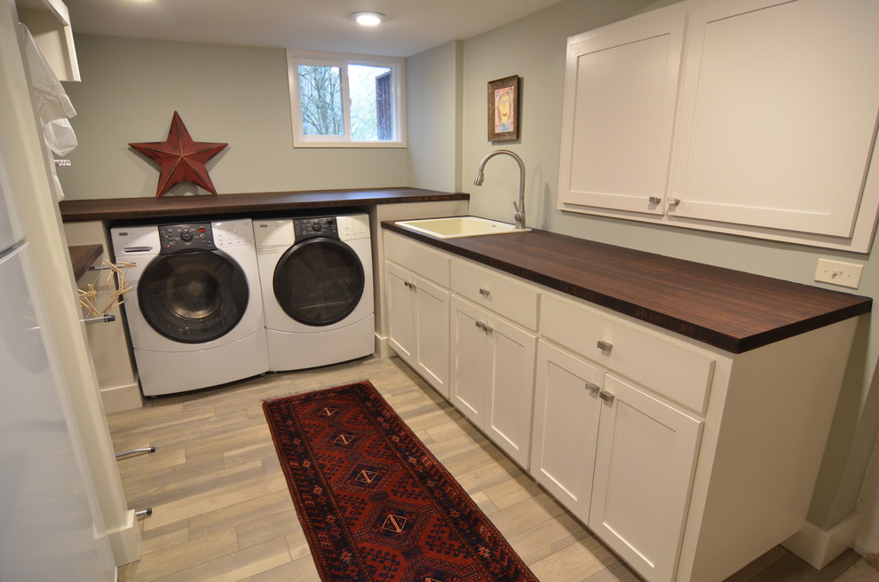 Inspiration for a large contemporary utility room in Portland with shaker cabinets, white cabinets, wood worktops, grey walls, ceramic flooring, a side by side washer and dryer and a built-in sink.