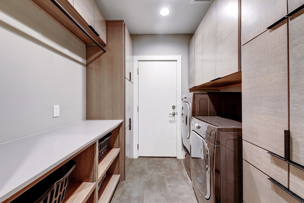 Foto di una piccola sala lavanderia moderna con ante lisce, ante in legno chiaro, top in quarzo composito, pareti grigie, pavimento con piastrelle in ceramica, lavatrice e asciugatrice affiancate e pavimento grigio