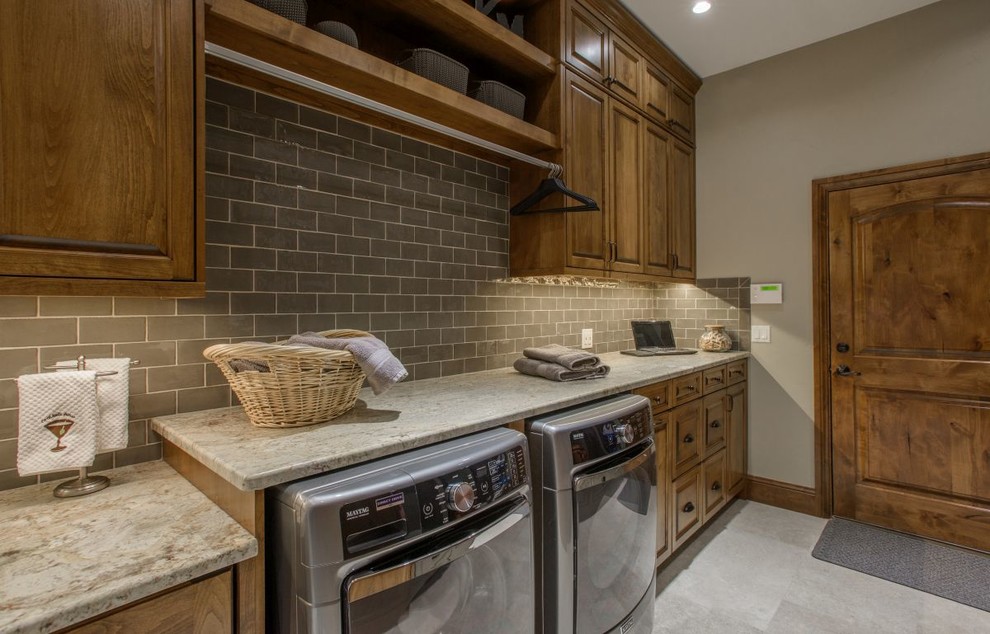 This is an example of a large traditional utility room in Denver with raised-panel cabinets, dark wood cabinets, granite worktops, grey walls, concrete flooring, a side by side washer and dryer and grey floors.