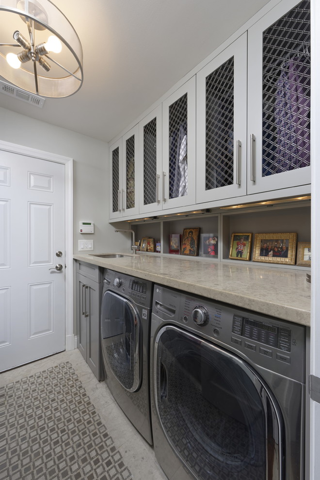 ワシントンD.C.にある中くらいなトランジショナルスタイルのおしゃれな家事室 (ll型、アンダーカウンターシンク、シェーカースタイル扉のキャビネット、グレーのキャビネット、ライムストーンカウンター、グレーの壁、大理石の床、左右配置の洗濯機・乾燥機、グレーの床、グレーのキッチンカウンター) の写真