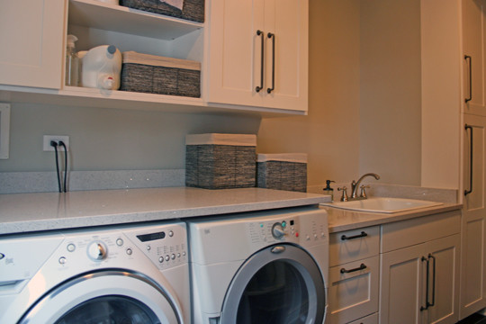Design ideas for a modern utility room in Chicago with white cabinets, beige walls and a side by side washer and dryer.