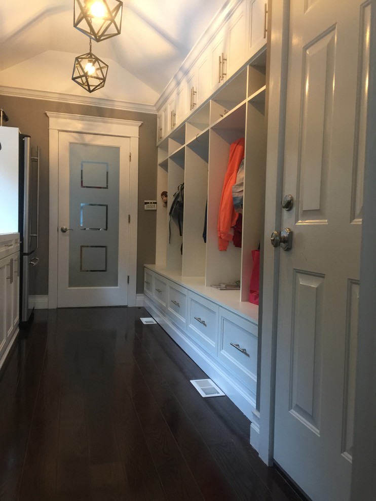This is an example of a large traditional utility room in New York with dark hardwood flooring, a stacked washer and dryer and brown floors.