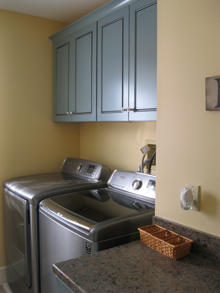 Exempel på ett litet klassiskt linjärt grovkök, med laminatbänkskiva, en tvättmaskin och torktumlare bredvid varandra, en nedsänkt diskho, beige väggar, vinylgolv, luckor med infälld panel och blå skåp