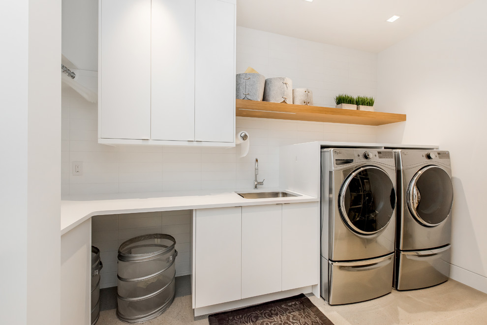 Inspiration for a large contemporary l-shaped utility room in Calgary with a submerged sink, flat-panel cabinets, white cabinets, engineered stone countertops, white walls, concrete flooring and a side by side washer and dryer.