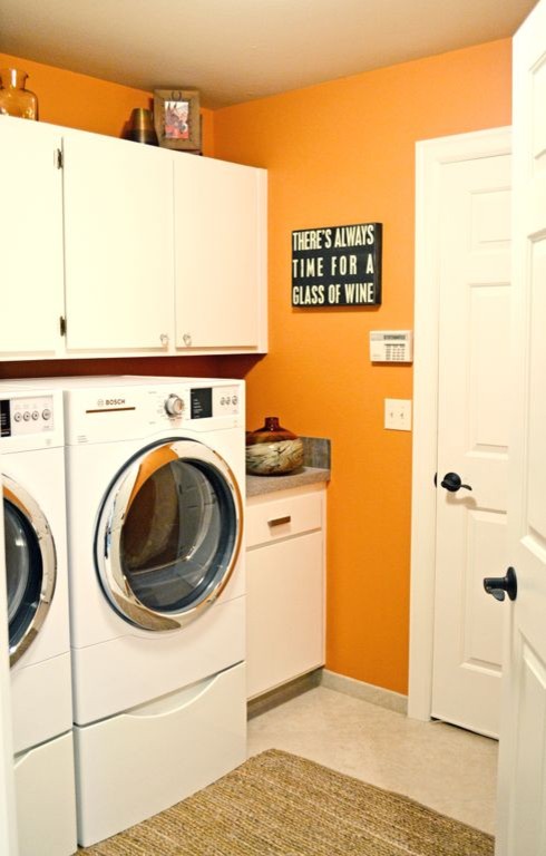 Design ideas for a contemporary galley utility room in Portland with flat-panel cabinets, white cabinets, orange walls and a side by side washer and dryer.