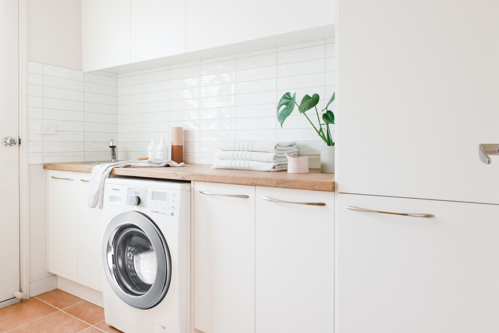 Foto på en mellanstor minimalistisk parallell tvättstuga enbart för tvätt, med en nedsänkt diskho, öppna hyllor, vita skåp, laminatbänkskiva, vita väggar, klinkergolv i terrakotta och en tvättmaskin och torktumlare bredvid varandra