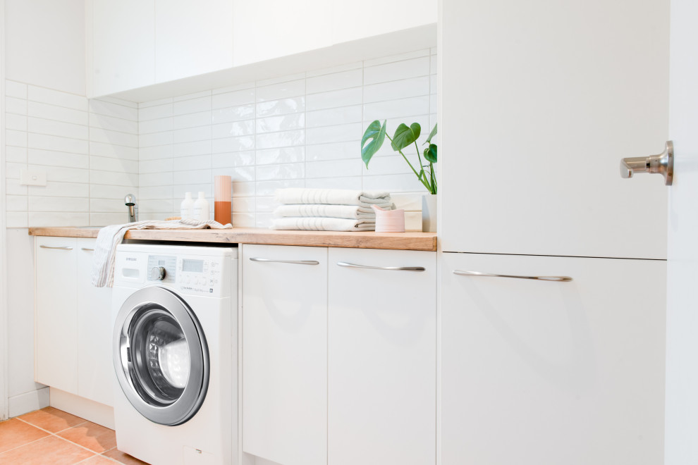 Foto på en mellanstor skandinavisk parallell tvättstuga enbart för tvätt, med en nedsänkt diskho, öppna hyllor, vita skåp, laminatbänkskiva, vita väggar, klinkergolv i terrakotta och en tvättmaskin och torktumlare bredvid varandra