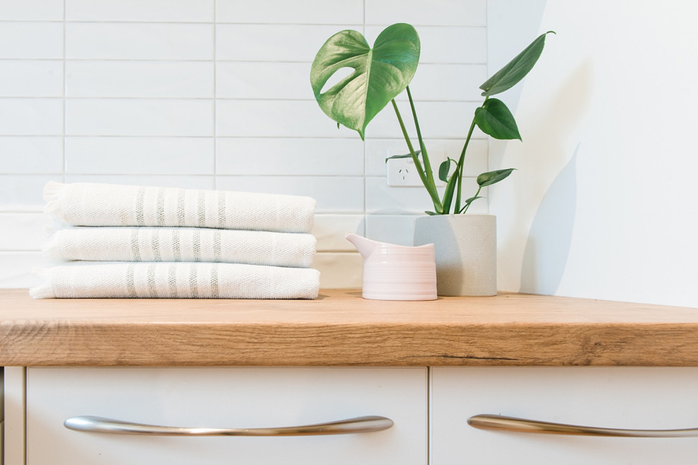 Exempel på en mellanstor minimalistisk parallell tvättstuga enbart för tvätt, med en nedsänkt diskho, öppna hyllor, vita skåp, laminatbänkskiva, vita väggar, klinkergolv i terrakotta och en tvättmaskin och torktumlare bredvid varandra