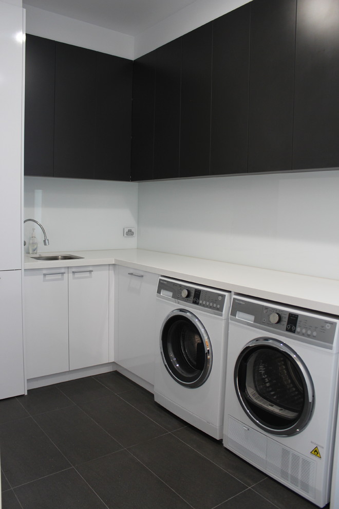 Foto di una lavanderia minimal con lavello da incasso, top in quarzo composito, pareti bianche, pavimento in gres porcellanato e lavatrice e asciugatrice affiancate