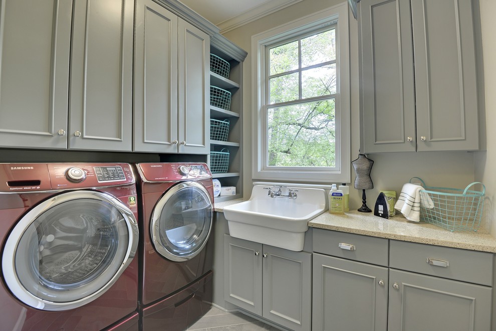 Inspiration för en stor vintage l-formad tvättstuga enbart för tvätt, med en rustik diskho, grå skåp, granitbänkskiva, beige väggar, en tvättmaskin och torktumlare bredvid varandra och luckor med infälld panel