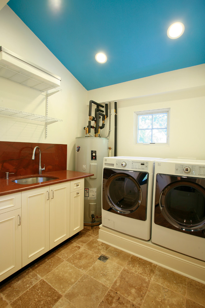 Inspiration för en mellanstor vintage tvättstuga enbart för tvätt, med en undermonterad diskho, vita skåp, granitbänkskiva, vita väggar, travertin golv och en tvättmaskin och torktumlare bredvid varandra
