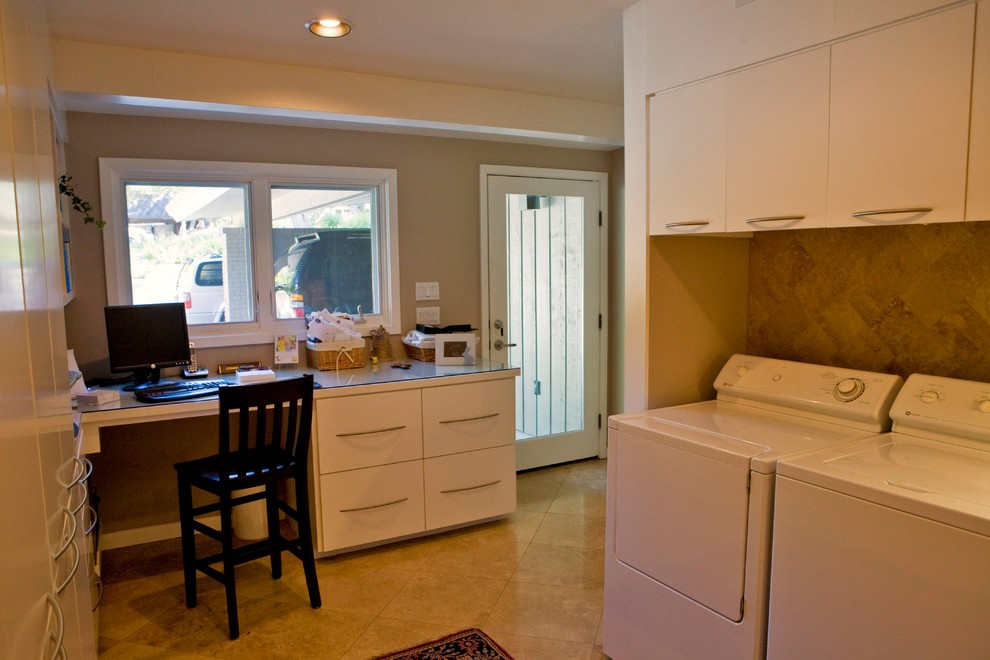 Example of a large 1950s u-shaped travertine floor utility room design in Austin with flat-panel cabinets, white cabinets, glass countertops, beige walls and a side-by-side washer/dryer