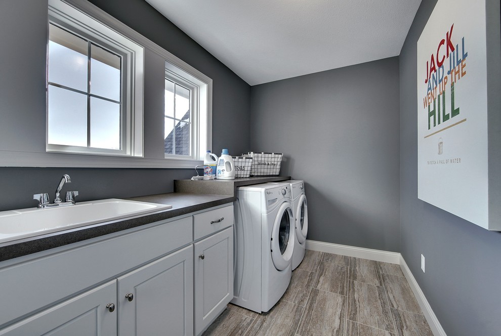 Dedicated laundry room - large transitional single-wall porcelain tile dedicated laundry room idea in Minneapolis with a drop-in sink, white cabinets, laminate countertops, gray walls and a side-by-side washer/dryer