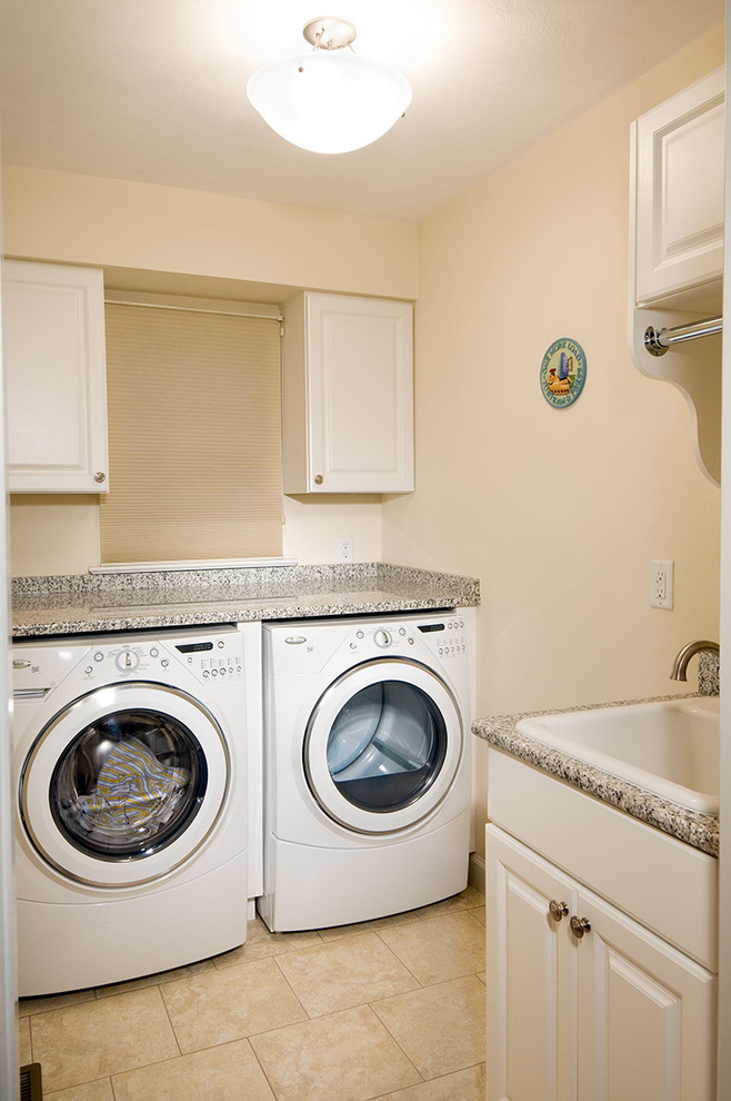 Idéer för små vintage l-formade tvättstugor enbart för tvätt, med en nedsänkt diskho, luckor med infälld panel, vita skåp, granitbänkskiva, beige väggar, klinkergolv i keramik, en tvättmaskin och torktumlare bredvid varandra och beiget golv