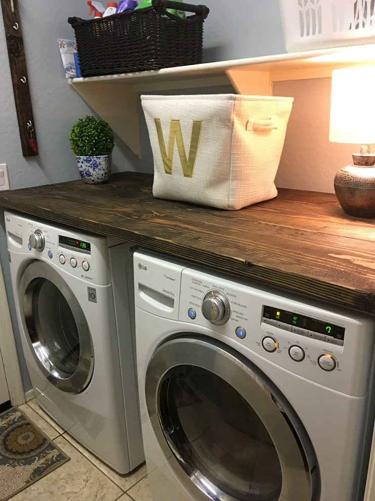 Foto di una piccola sala lavanderia country con top in legno, pavimento con piastrelle in ceramica, lavatrice e asciugatrice affiancate, top marrone e pareti grigie
