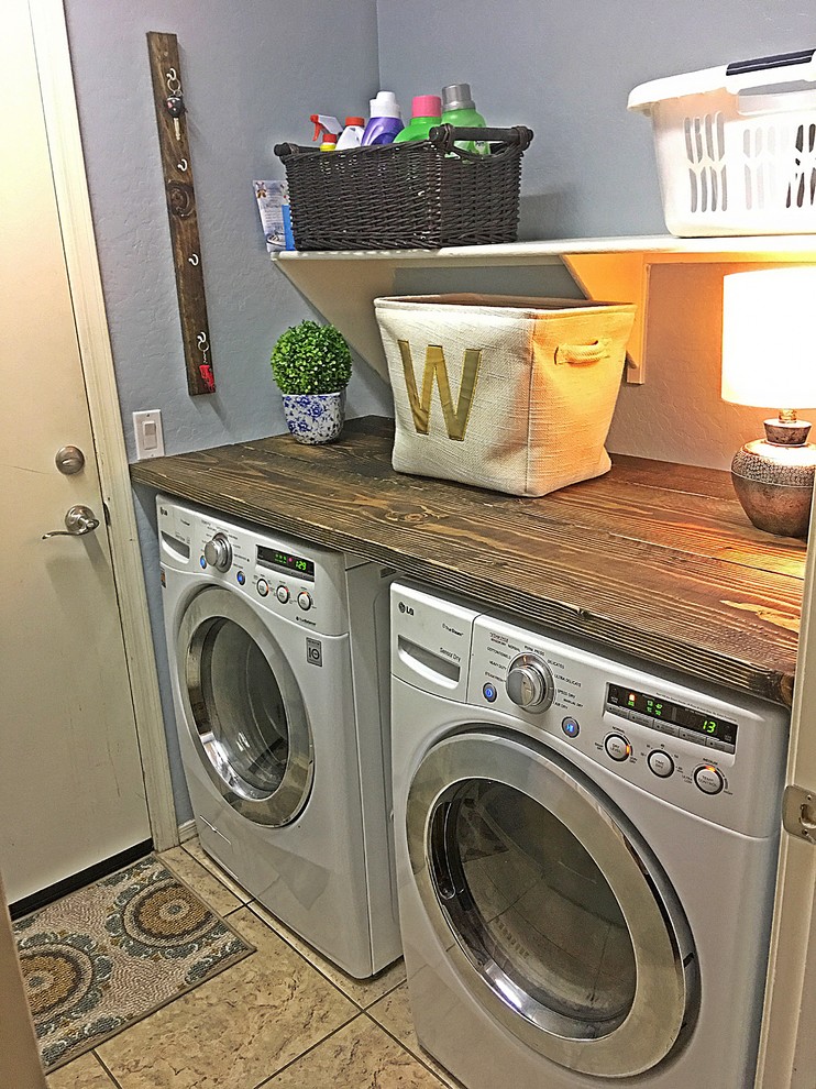Foto på en liten lantlig parallell tvättstuga enbart för tvätt, med träbänkskiva, blå väggar, klinkergolv i keramik och en tvättmaskin och torktumlare bredvid varandra