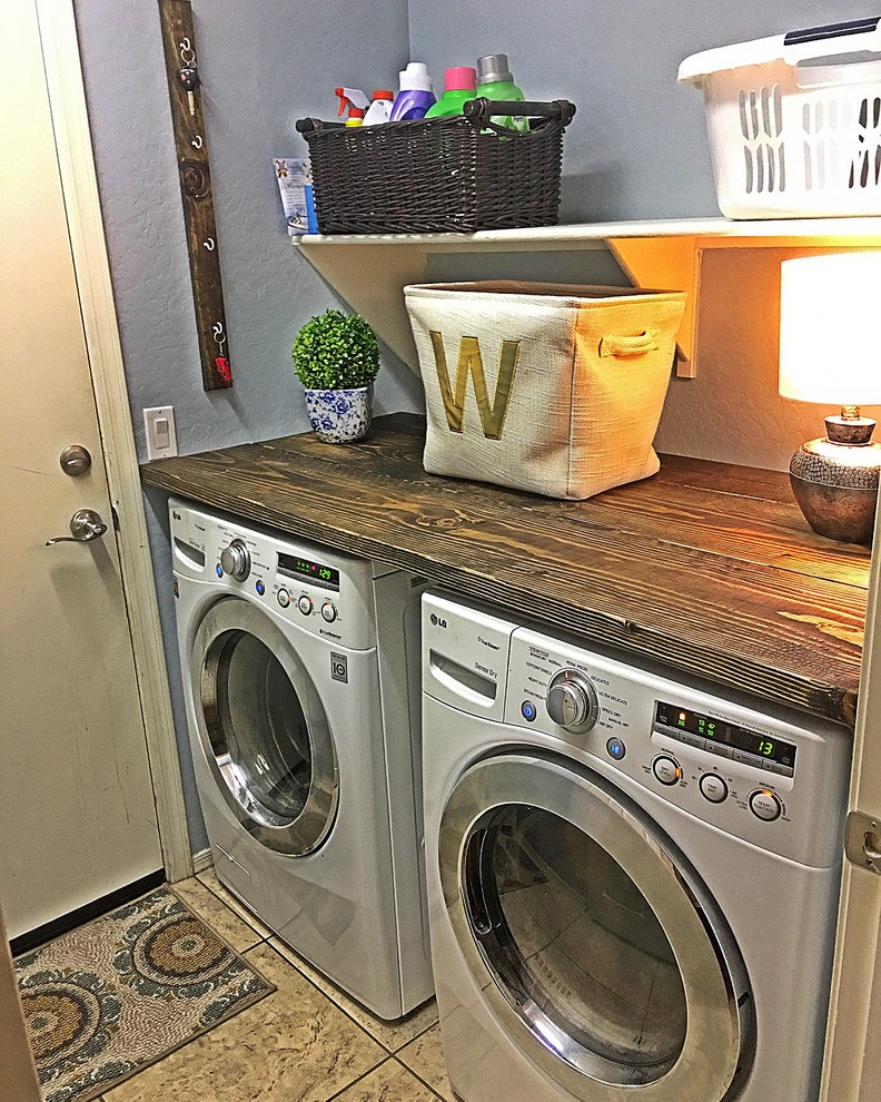 Exempel på en liten lantlig parallell tvättstuga enbart för tvätt, med träbänkskiva, blå väggar, klinkergolv i keramik och en tvättmaskin och torktumlare bredvid varandra
