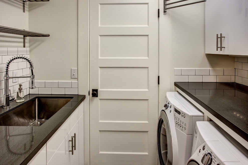 Inspiration for a traditional separated utility room in Seattle with a single-bowl sink, flat-panel cabinets, white cabinets, white walls and a side by side washer and dryer.