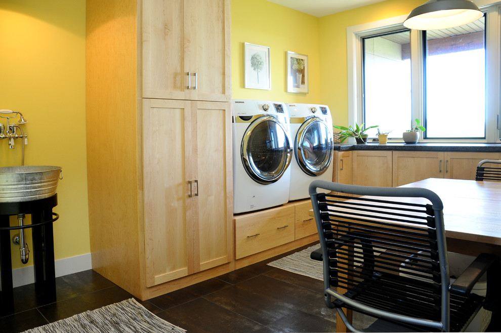 Idee per una grande lavanderia multiuso moderna con lavatoio, ante in legno chiaro, top in quarzite, pareti gialle e lavatrice e asciugatrice affiancate