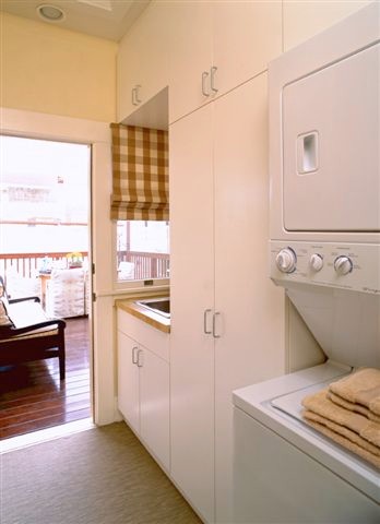 Esempio di una piccola sala lavanderia design con lavello da incasso, ante lisce, ante bianche, top in granito, pareti beige e lavatrice e asciugatrice a colonna