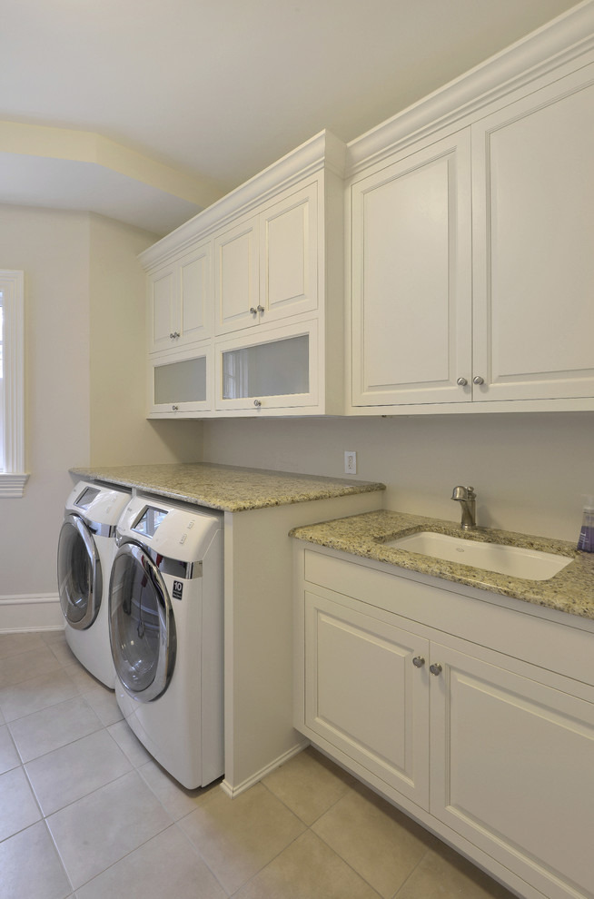 Dedicated laundry room - mid-sized traditional single-wall porcelain tile and beige floor dedicated laundry room idea in New York with an undermount sink, raised-panel cabinets, white cabinets, granite countertops, beige walls, a side-by-side washer/dryer and beige countertops