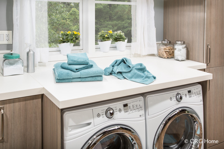 Dedicated laundry room - transitional single-wall medium tone wood floor dedicated laundry room idea in Columbus with an undermount sink, flat-panel cabinets, medium tone wood cabinets, solid surface countertops, gray walls and a side-by-side washer/dryer