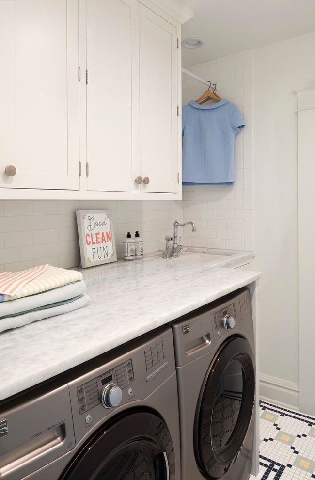 Exempel på en liten minimalistisk parallell tvättstuga enbart för tvätt, med en nedsänkt diskho, luckor med infälld panel, vita skåp, marmorbänkskiva, vita väggar, klinkergolv i porslin och en tvättmaskin och torktumlare bredvid varandra