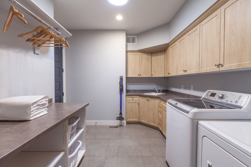 Inspiration for a mid-sized contemporary galley porcelain tile and gray floor dedicated laundry room remodel in Denver with a drop-in sink, shaker cabinets, light wood cabinets, laminate countertops, blue walls, a side-by-side washer/dryer and gray countertops